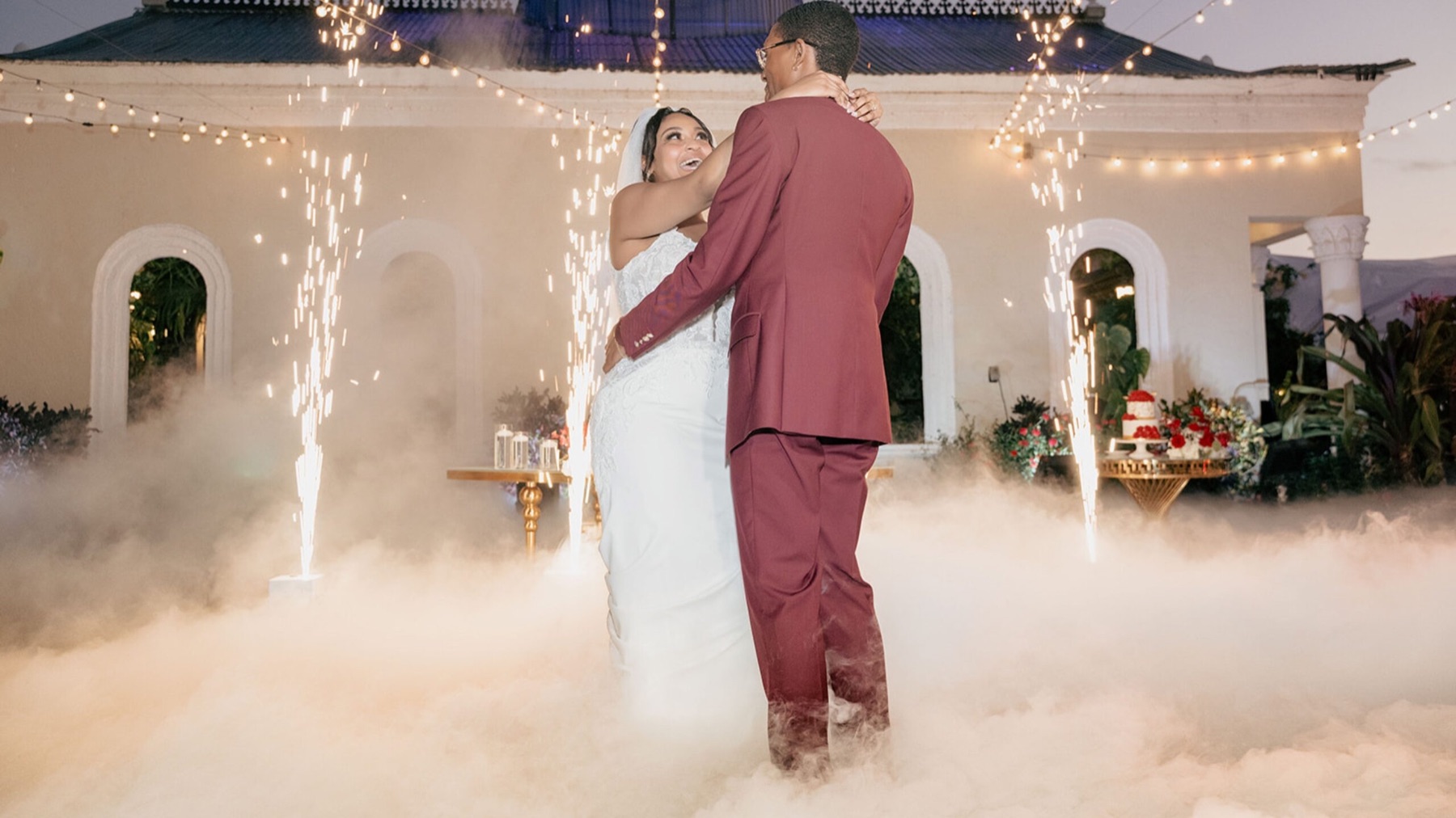 Bride and groom dancing in low fog beside cold sparks