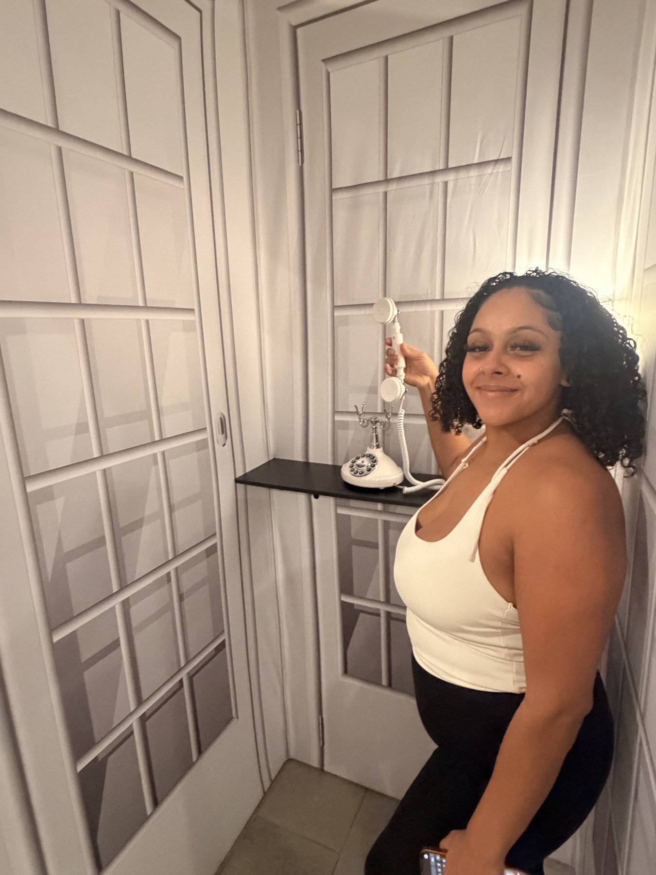 Guest posing with a vintage telephone at a white door backdrop