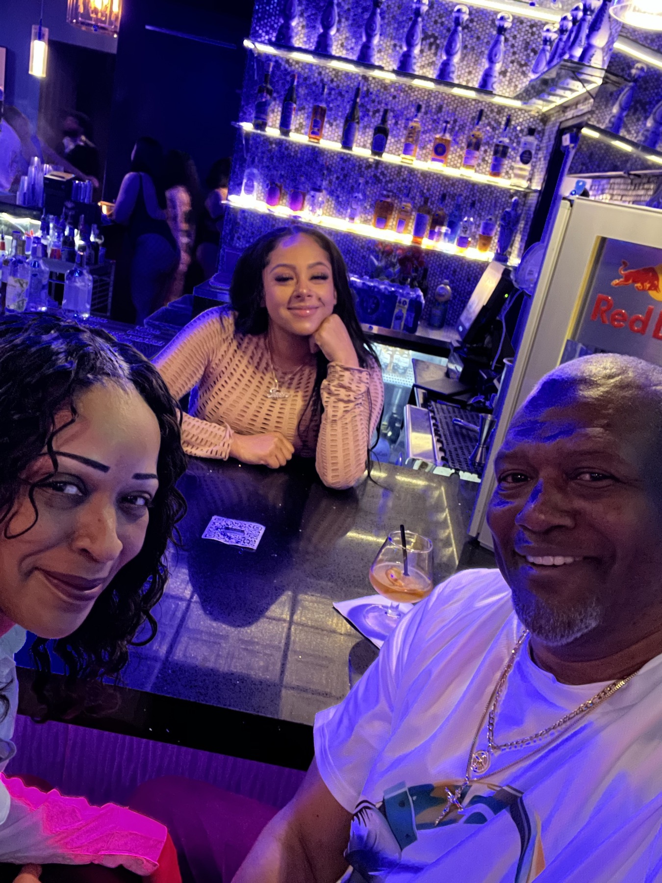 Selfie with two guests at a bar with backlit bottle shelves