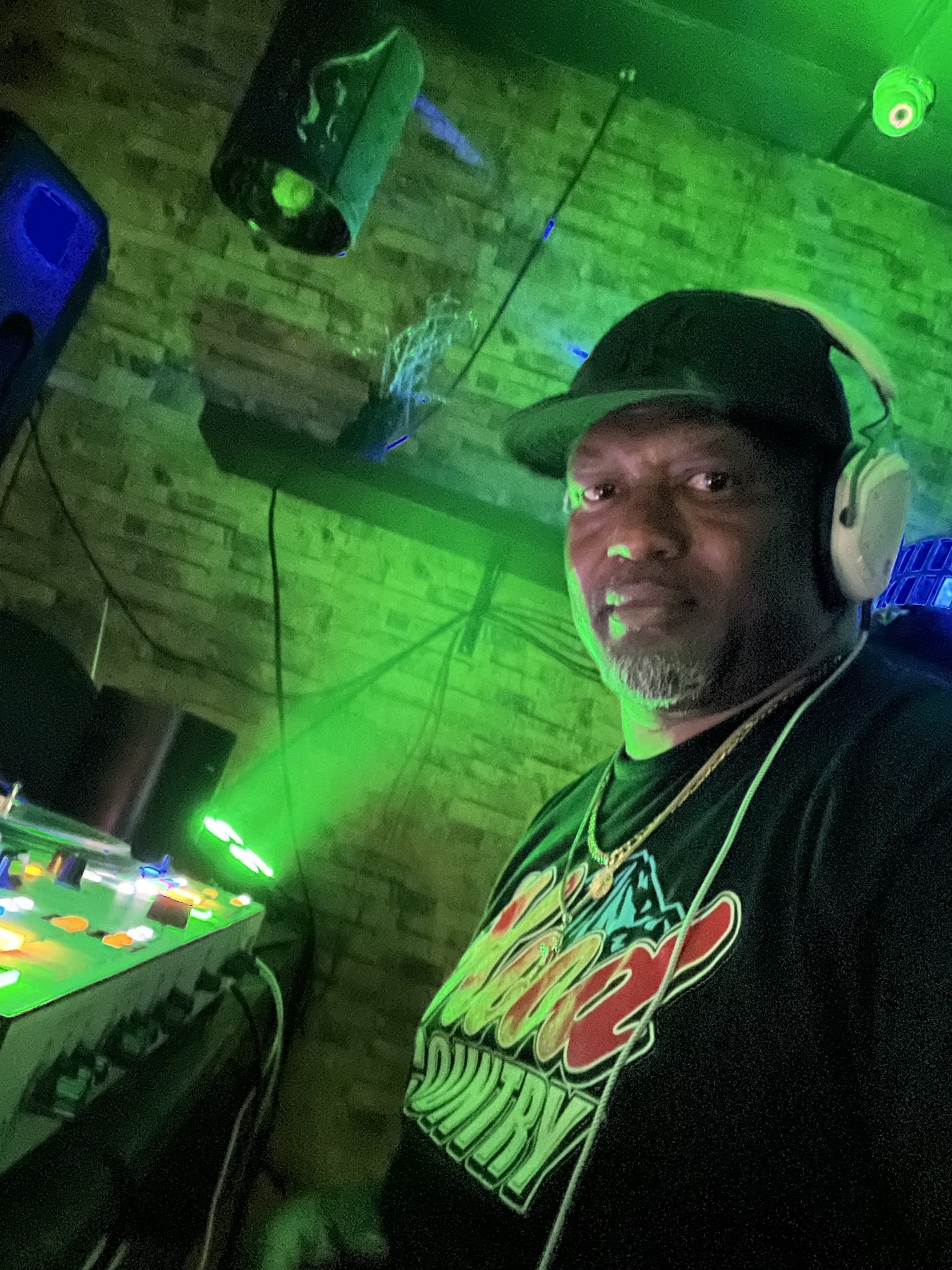 DJ in headphones taking a selfie at the decks under green lights