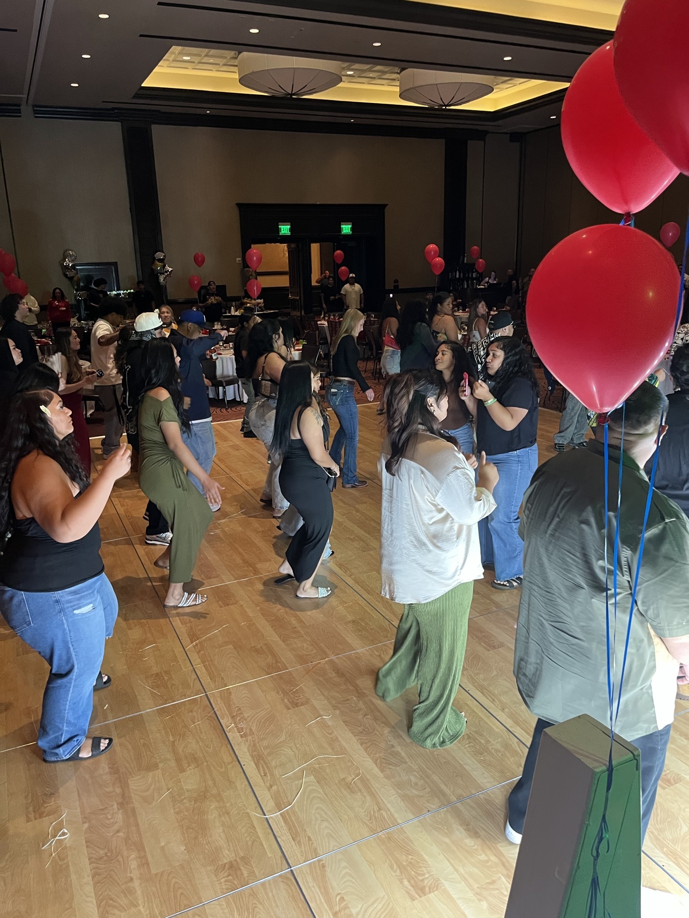 Guests dancing on a crowded dance floor with red balloons