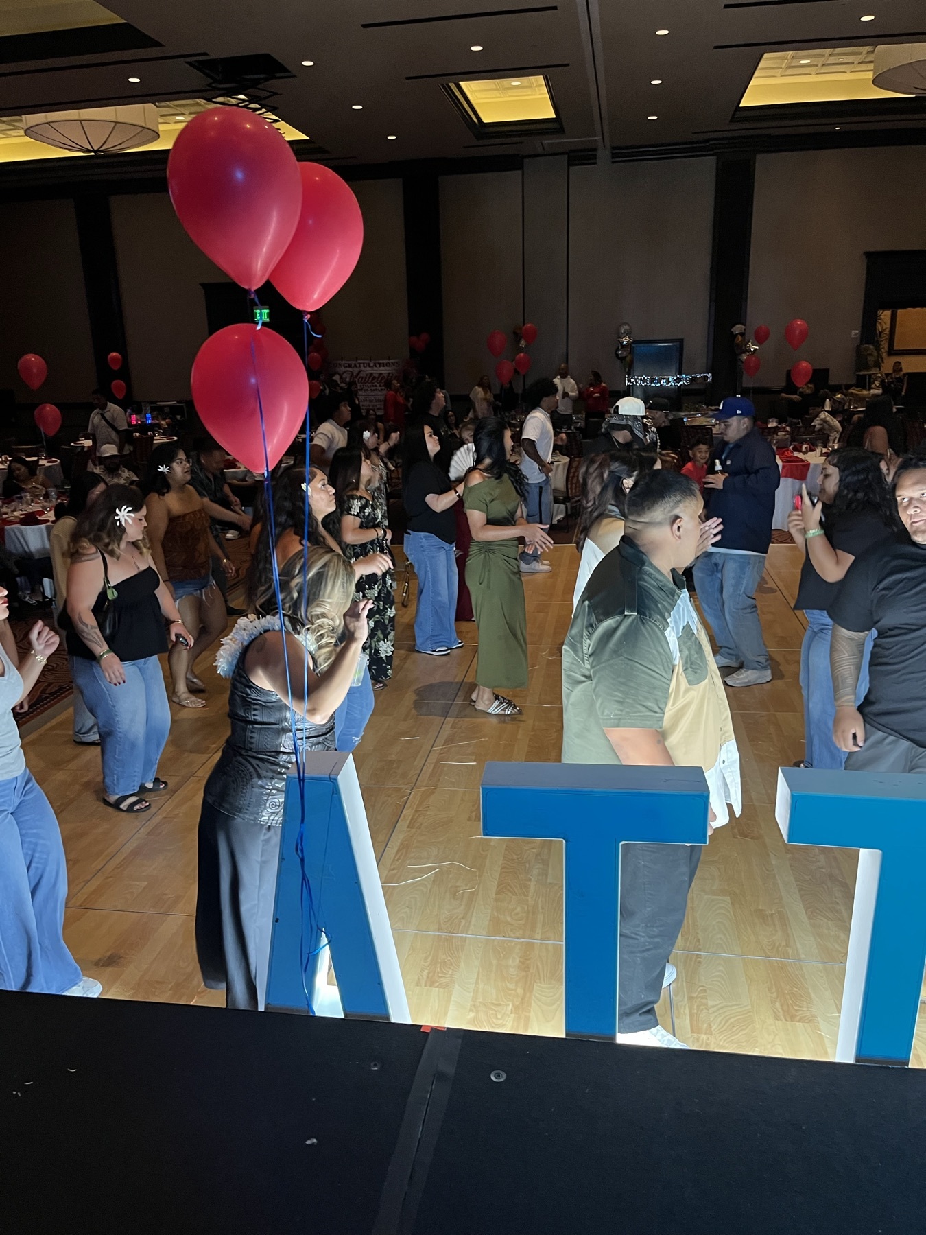 Guests dancing behind large blue letters and red balloons
