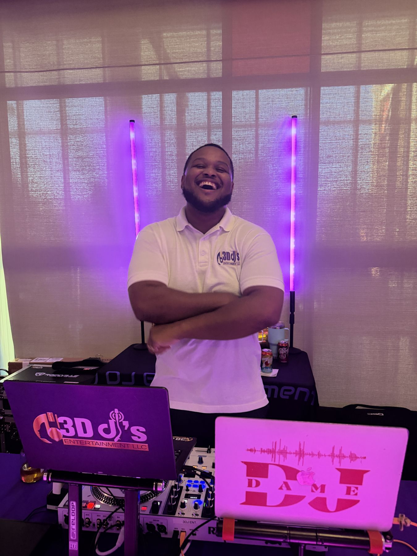 DJ laughing with arms crossed behind branded laptops