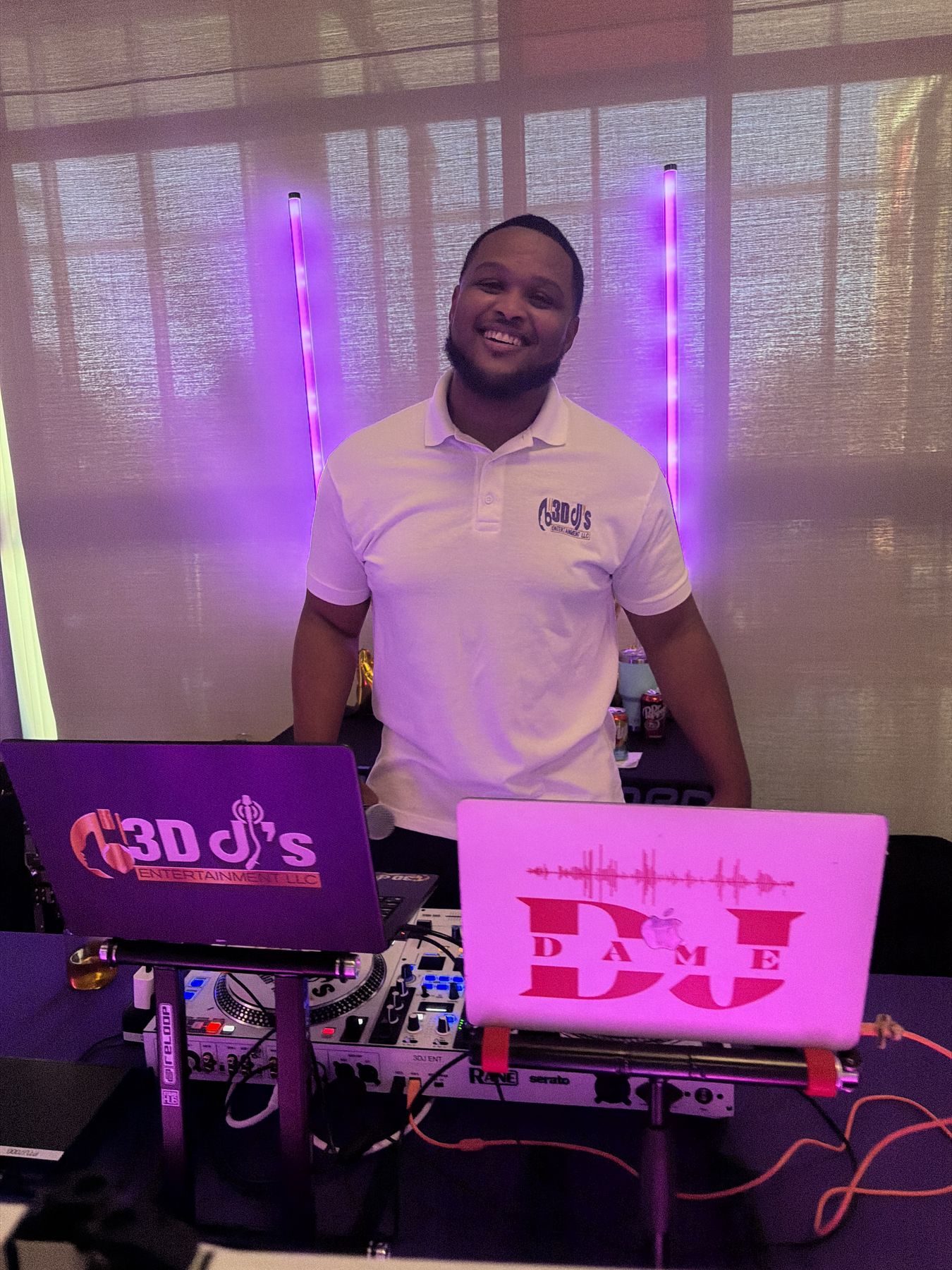 Smiling DJ standing behind branded laptops and decks