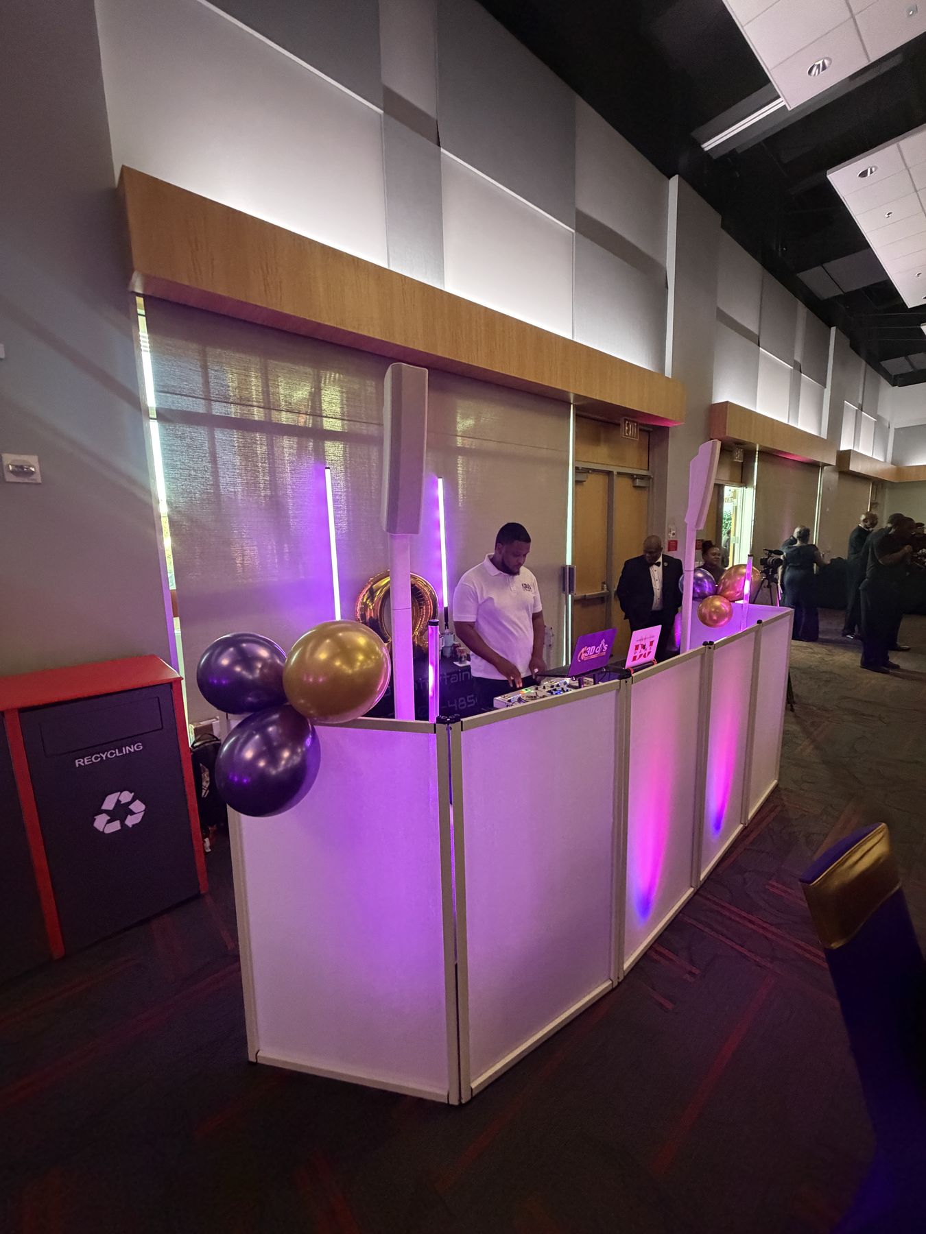 Full DJ facade with purple and gold balloons in a large event hall