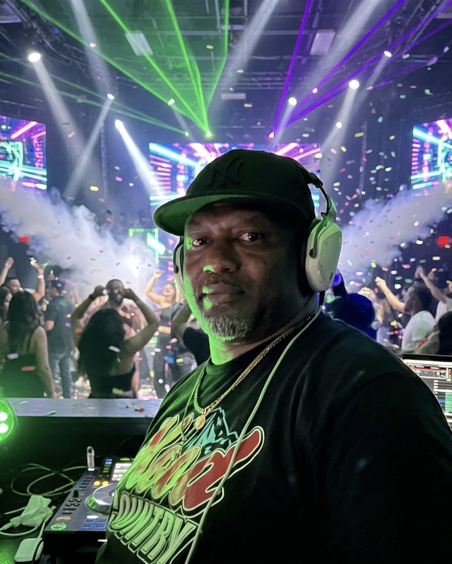 DJ in headphones with confetti and lasers over the crowd
