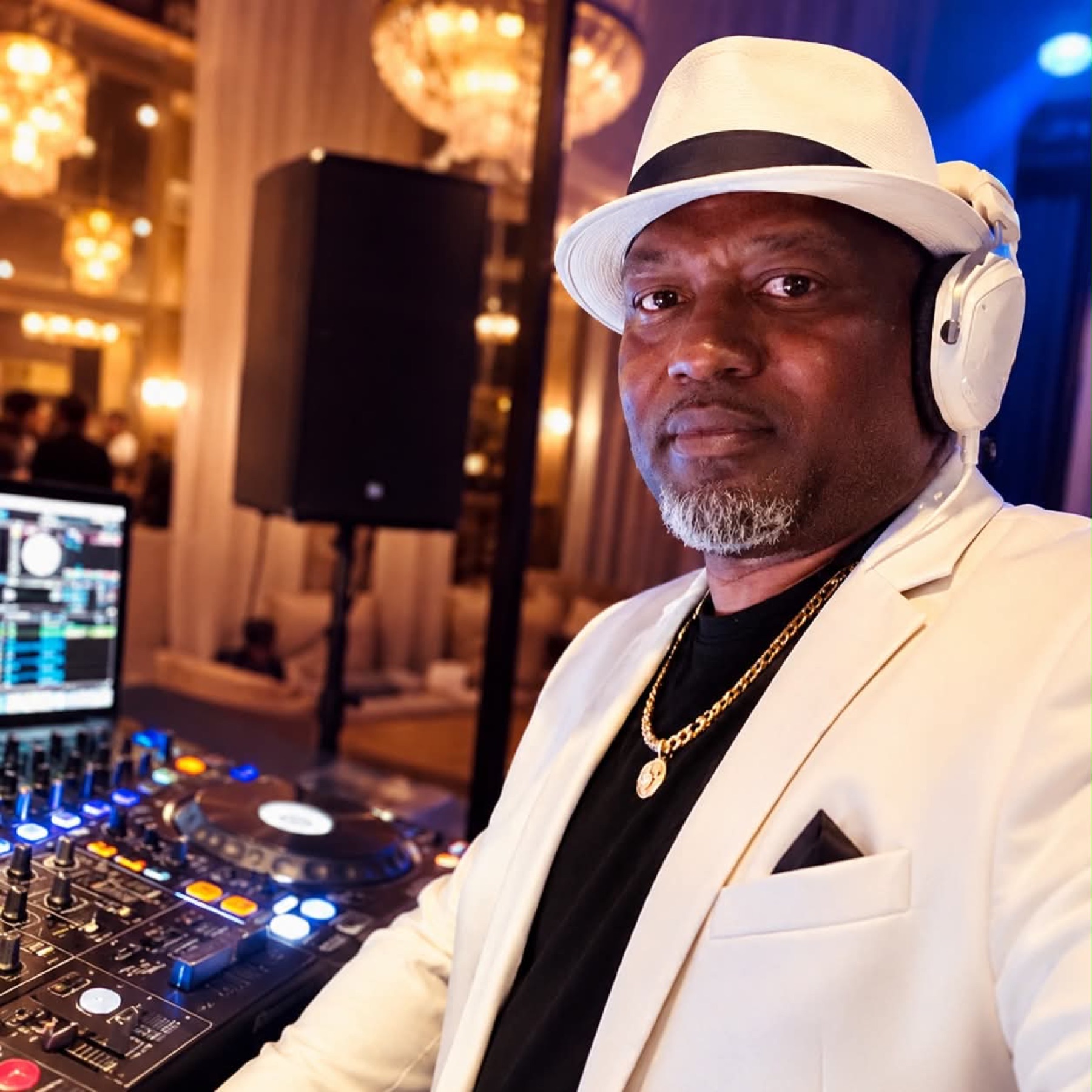 DJ in a white hat and headphones taking a selfie at the controller