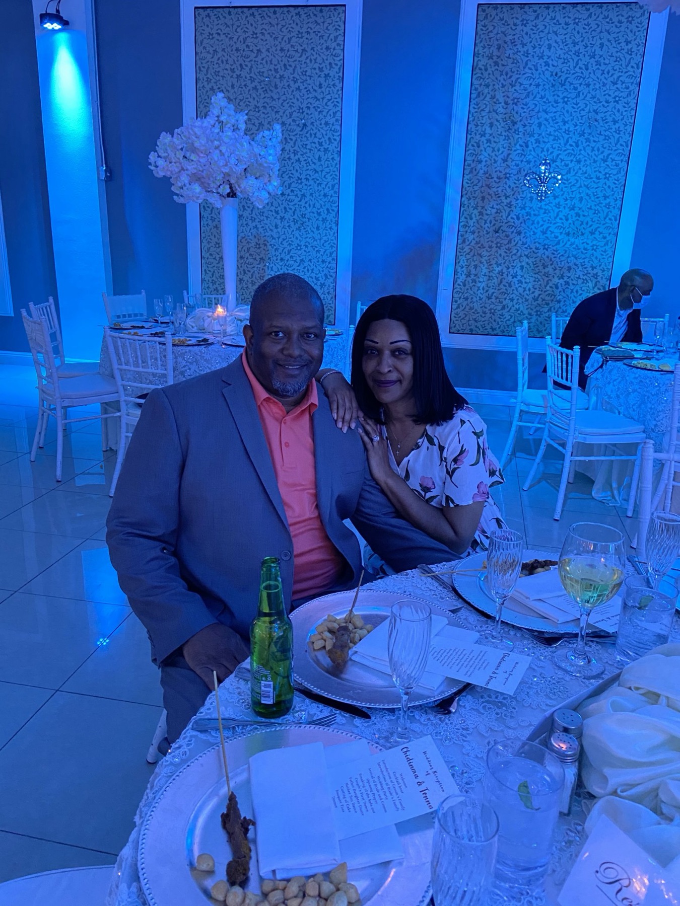 Couple seated at a reception table under blue uplighting