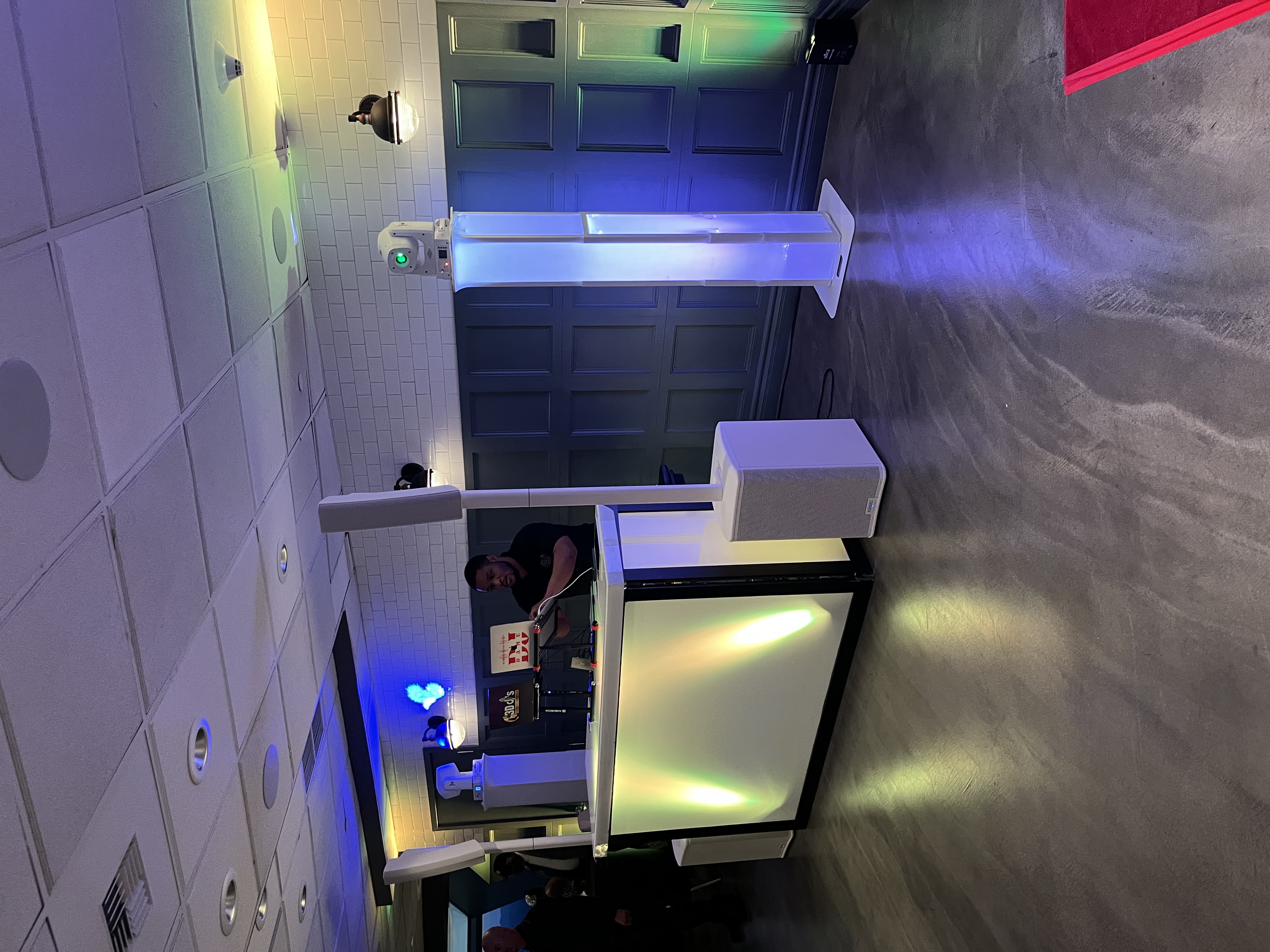 DJ behind booth with lighting and speakers at event